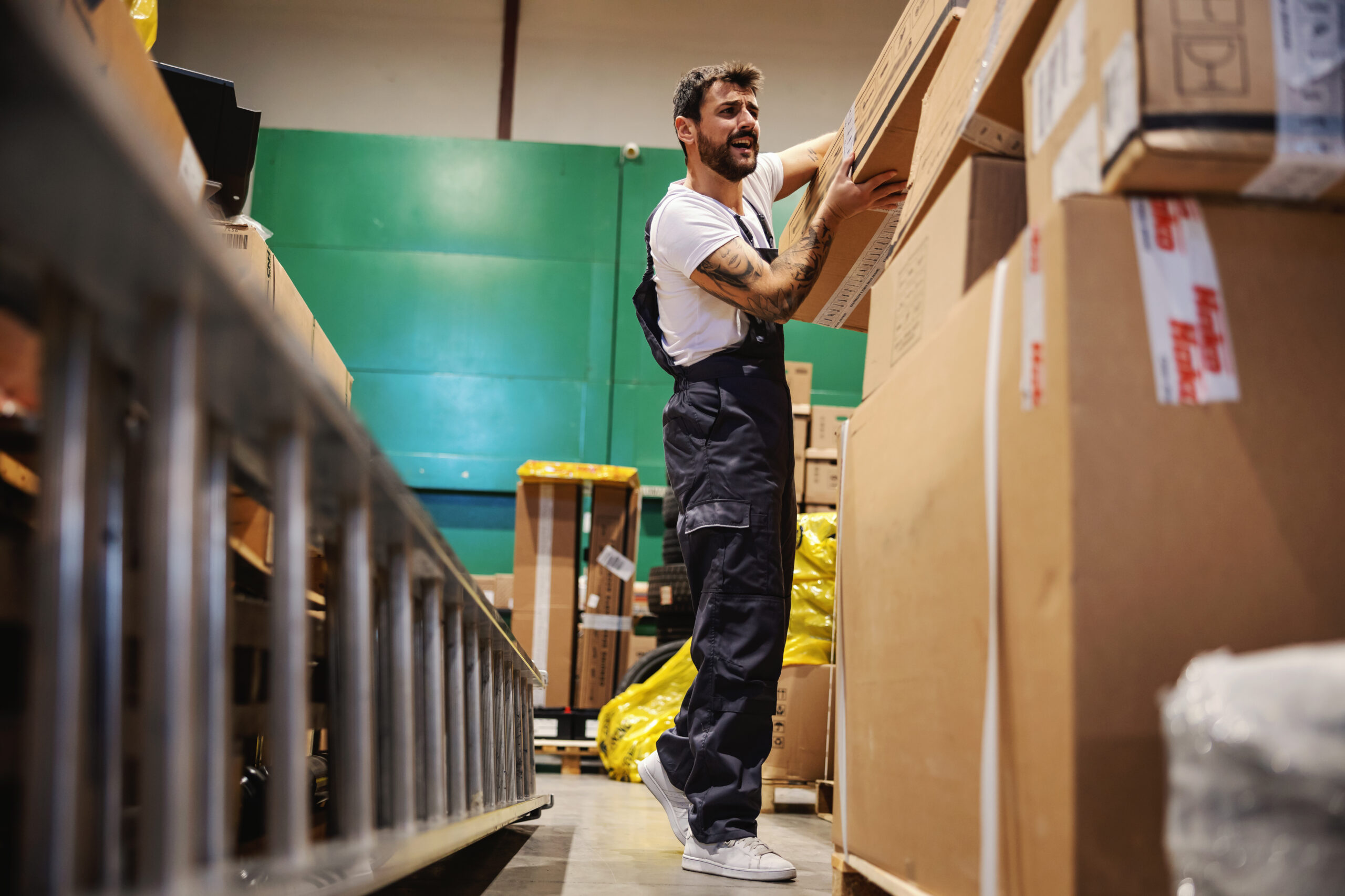 Manual worker lifting heavy box in warehouse