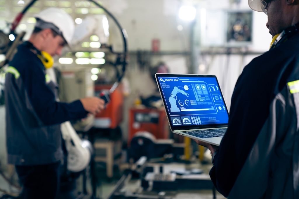 Factory workers working with adept robotic arm in a workshop